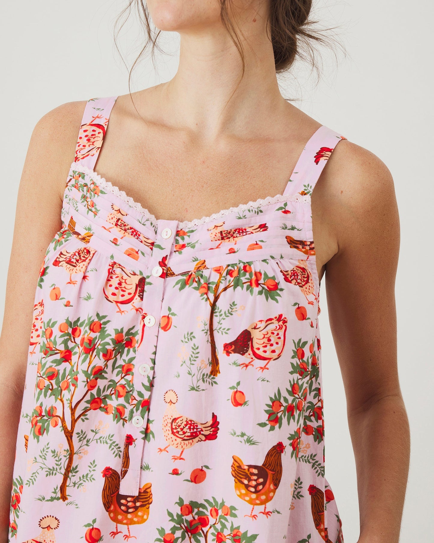 Close-up front view of the nightgown showing the lace-trimmed neckline, buttons, gathered bodice, and hen-and-fruit print.