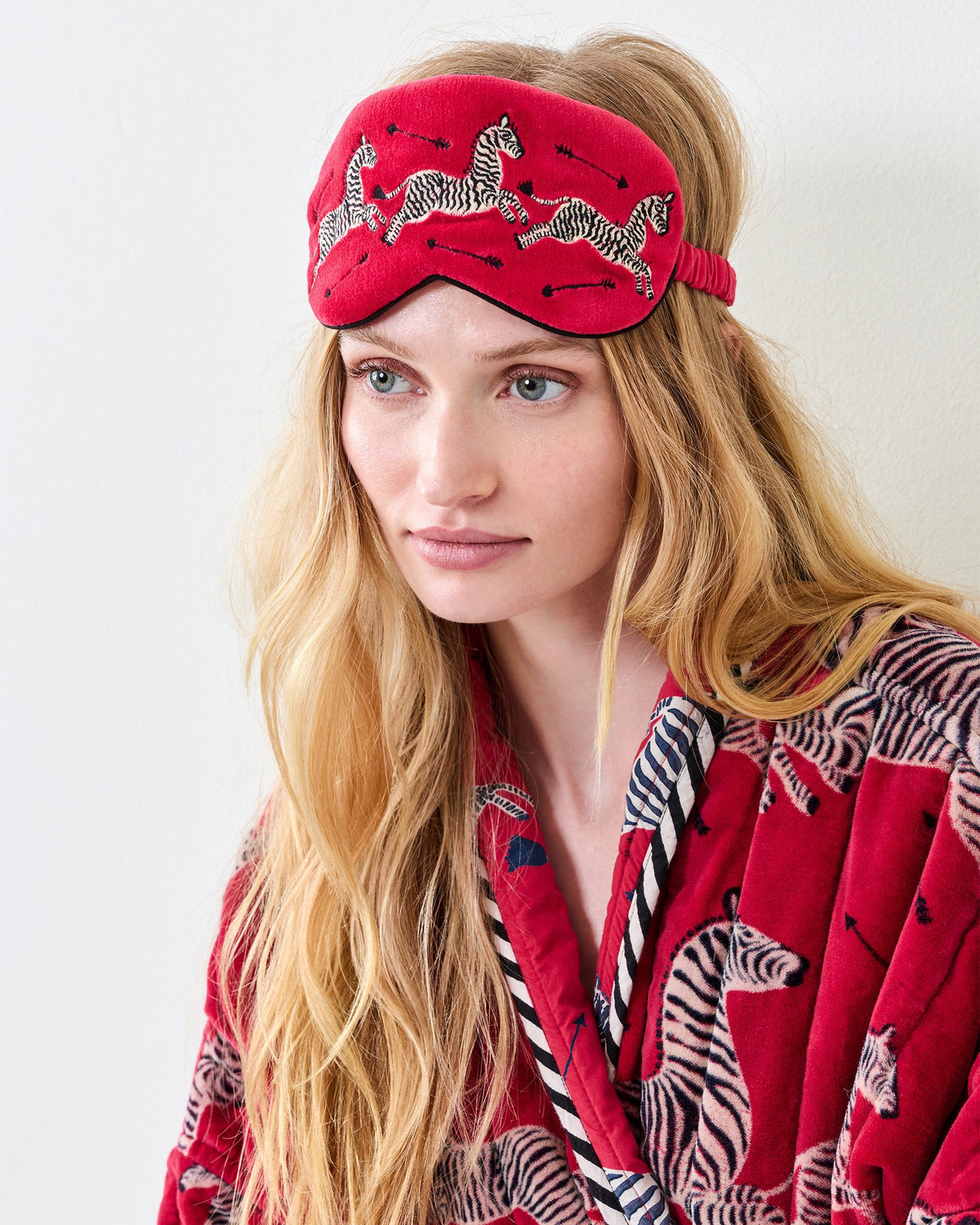Person wearing a red embroidered zebra-print eye mask on the forehead, with the elastic band visible.