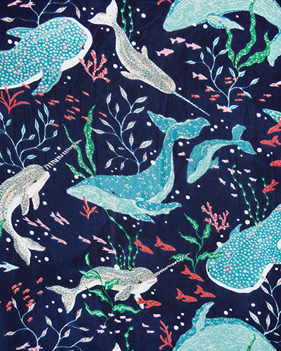 Navy fabric swatch with a repeating pattern of whales, narwhals, fish, coral, and seaweed.