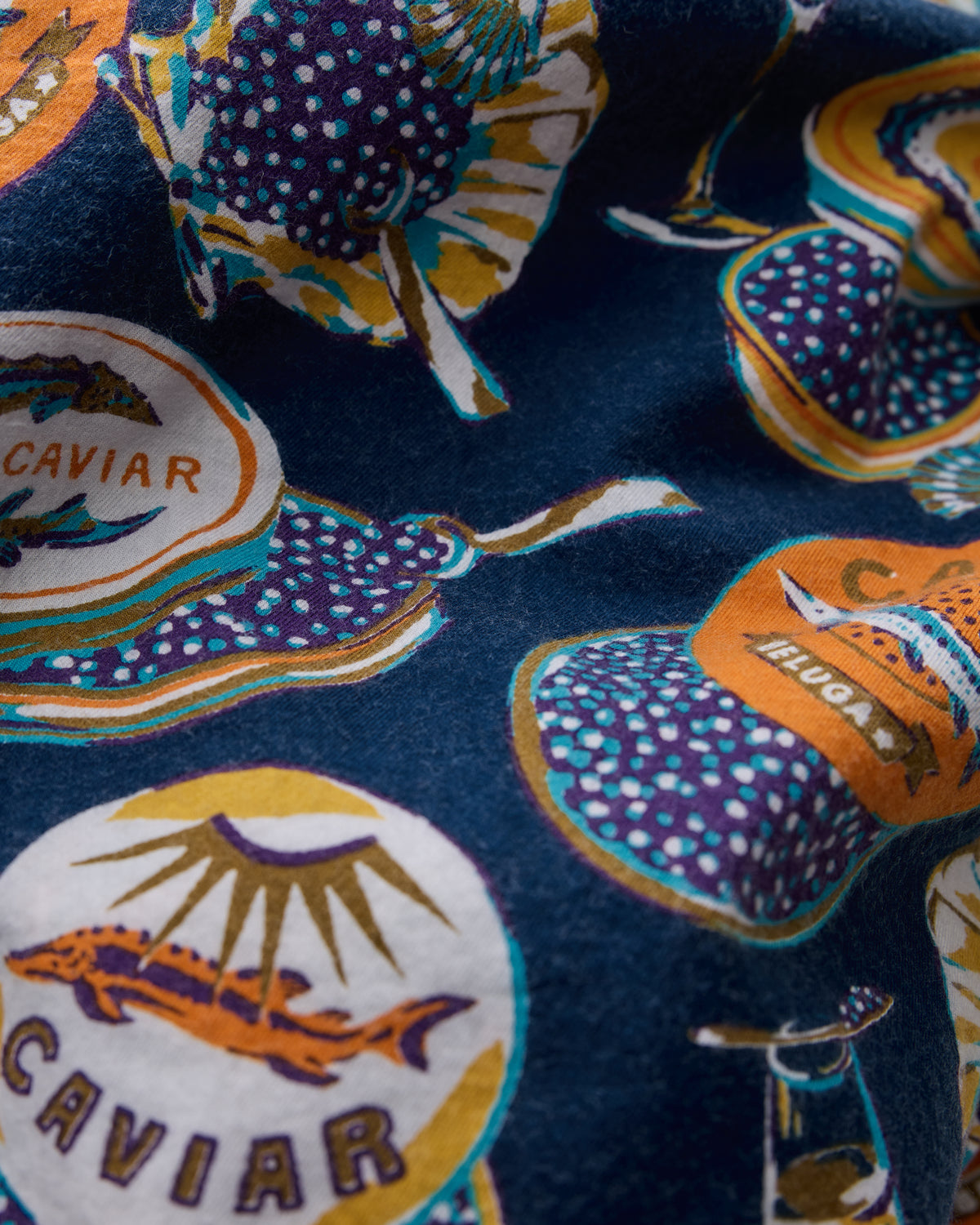 Navy fabric swatch with illustrated caviar tins, fish, and oyster shells.