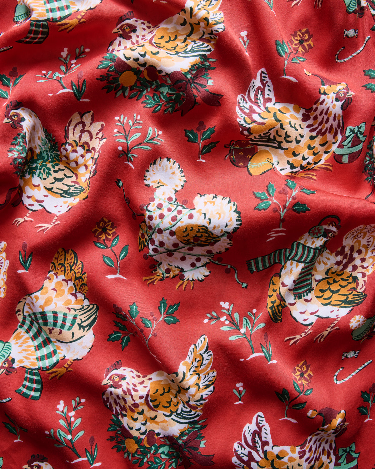 Close-up of the red Holiday Hens print featuring chickens, botanical sprigs, and decorative accents.