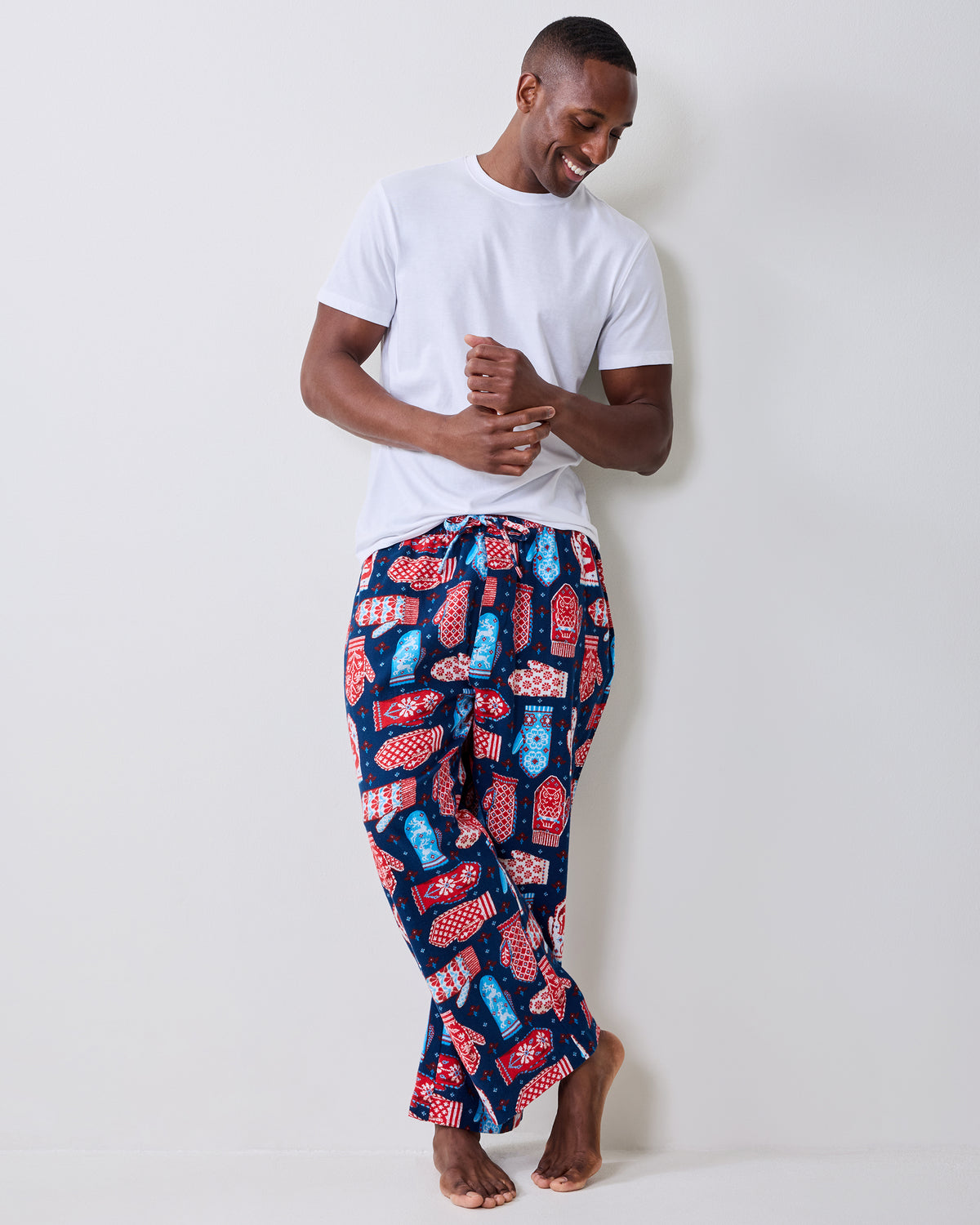 Model wearing the navy Nordic Mittens long pajama pants with a white T-shirt, showing the colorful mitten print and relaxed fit.