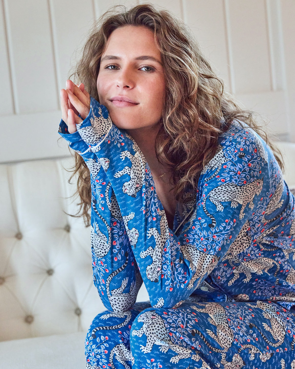 Model seated in the indigo leopard-print long pajama set, with hands resting beside the face
