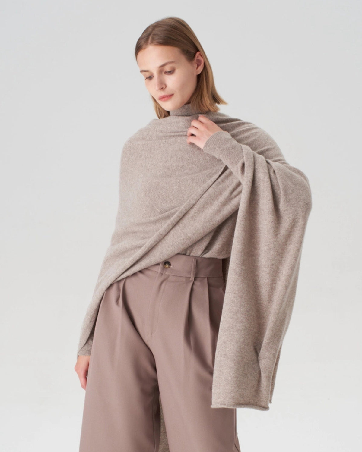 Oatmeal cashmere travel wrap draped over a model's shoulders, showing its wide shape and long pointed ends.