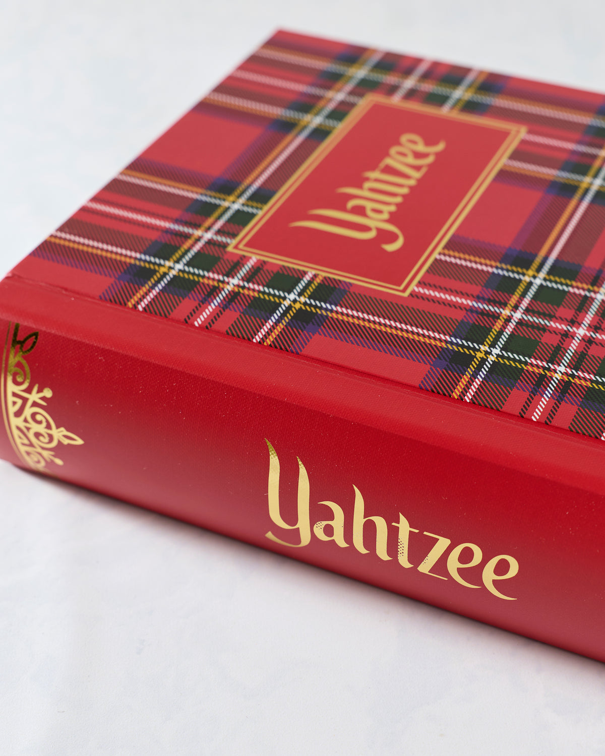 Close-up of the red plaid Yahtzee bookshelf-style game case with gold lettering and border.