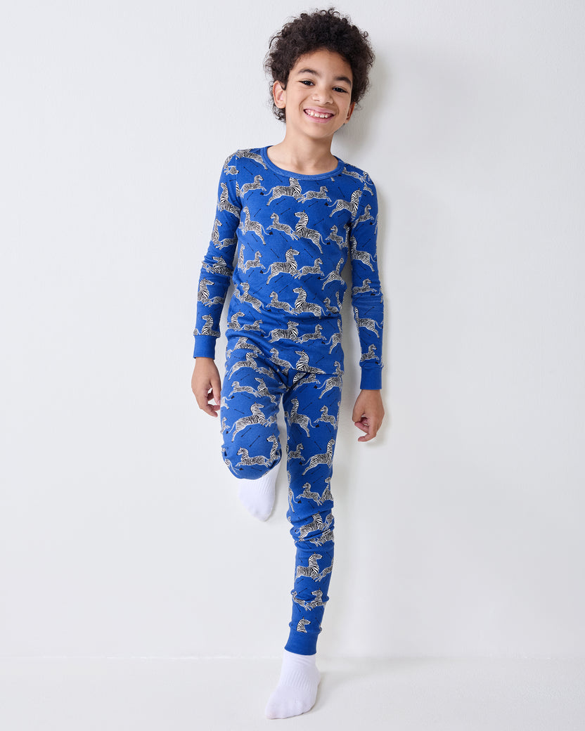 Model wearing a blue long-sleeve pajama top and matching pants with a zebra-and-arrow print.