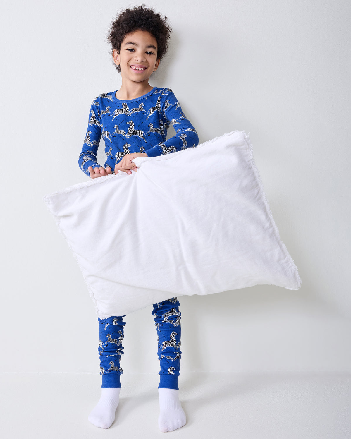 Model wearing the blue zebra-and-arrow pajama set while holding a white pillow.