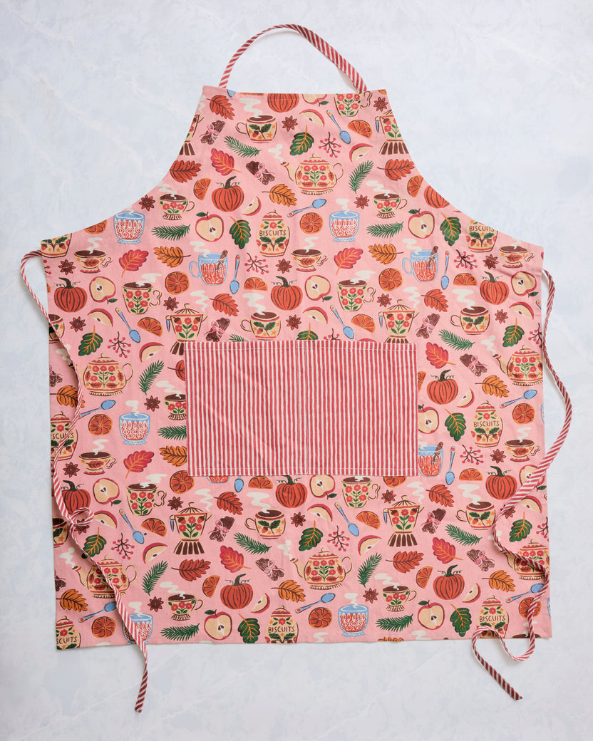 Rose-pink autumn print apron with striped neck strap, waist ties, and a large striped front pocket.