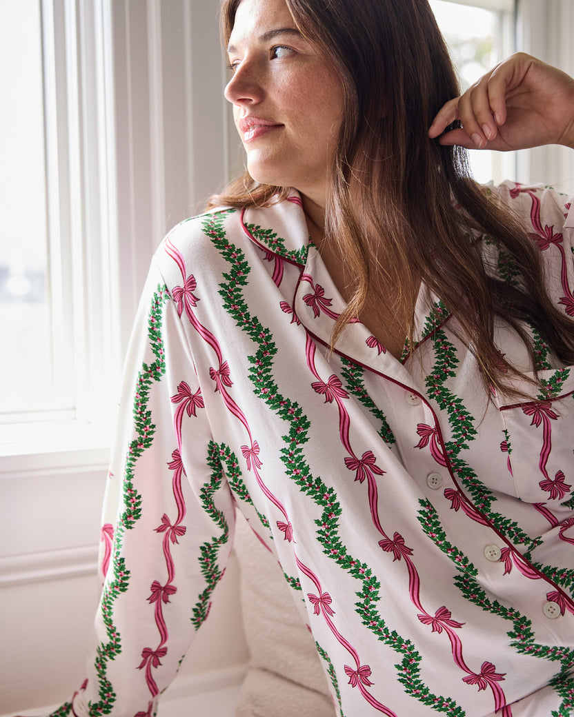 Close view of the Ribbons & Bows pajama top showing its collar, buttons, and pink bow and green garland print.