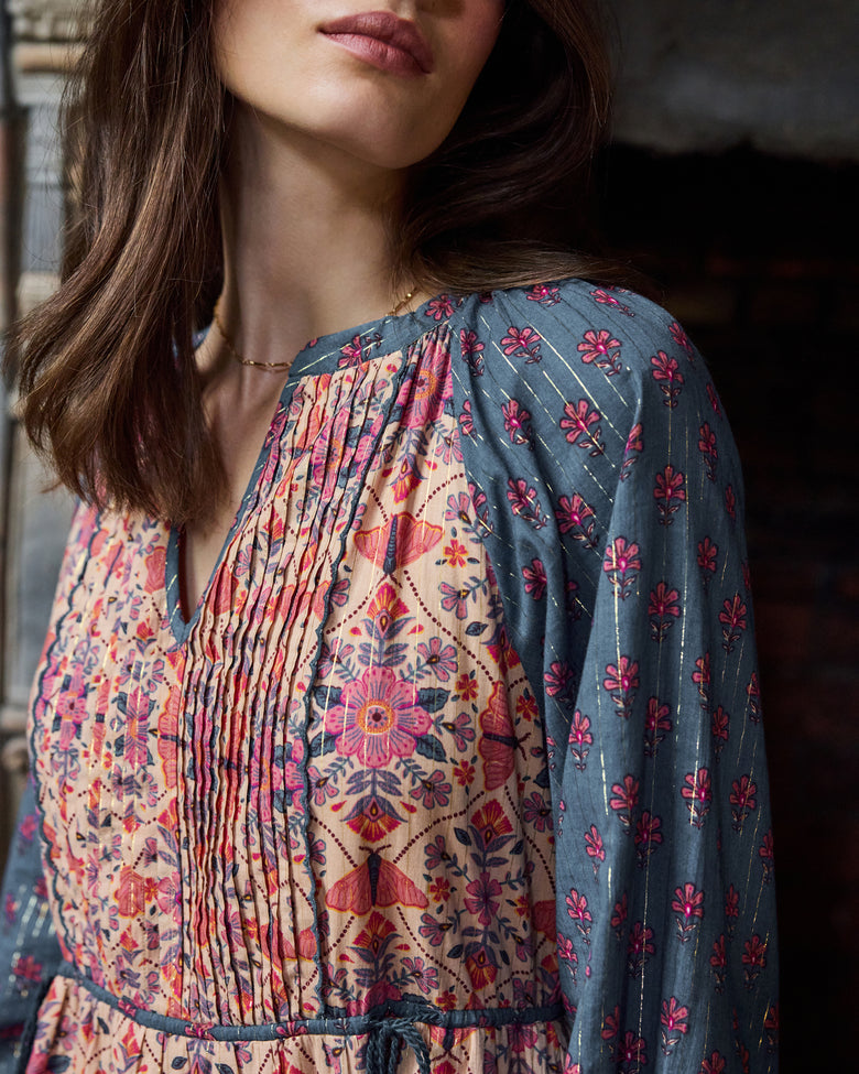 Close-up of the Winged Tapestry Eden Dress showing the pleated floral-print bodice and blue patterned sleeve.