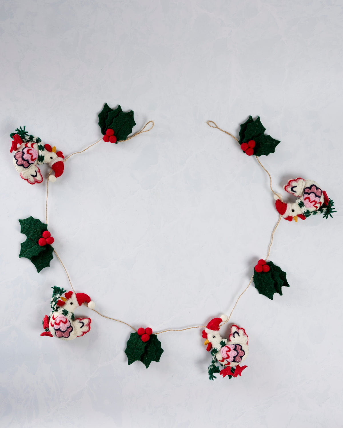 Holiday hens garland arranged in a circle, with four felt hens in Santa hats alternating with holly leaves and red berries.