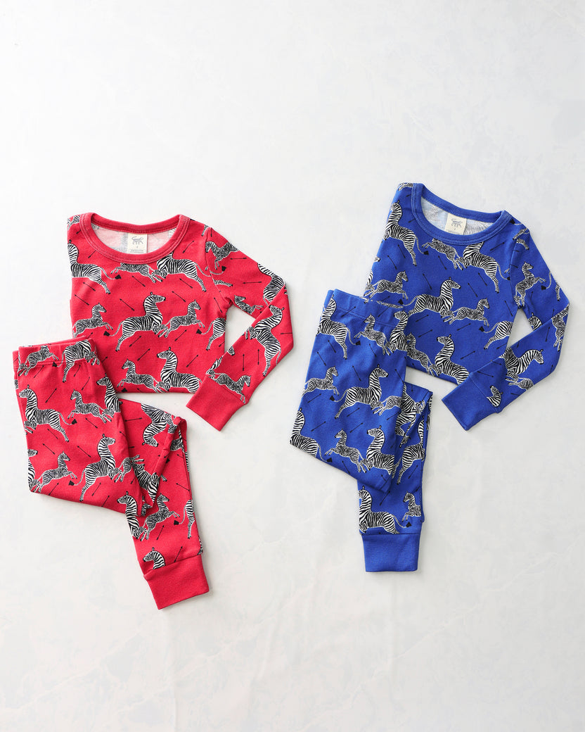 Two zebra-print children’s pajama sets, one red and one blue, each with a long-sleeve top and pants.