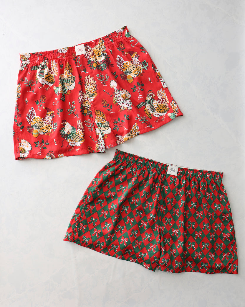 Two Printfresh boyfriend boxer shorts: red shorts with illustrated holiday hens and green argyle shorts with bow motifs.