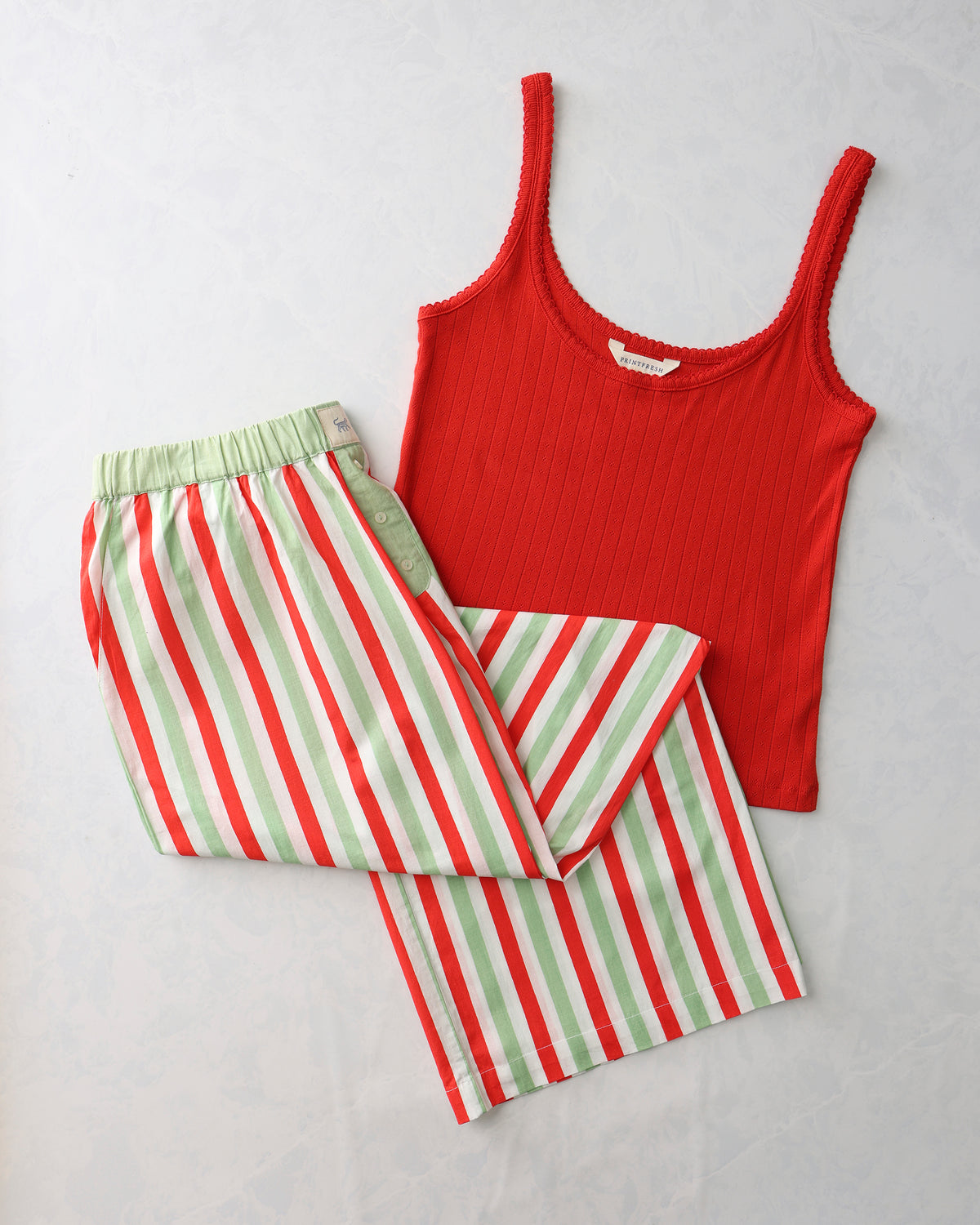 Red ribbed tank top paired with wide-leg pajama pants featuring red, white, and pale green vertical stripes.