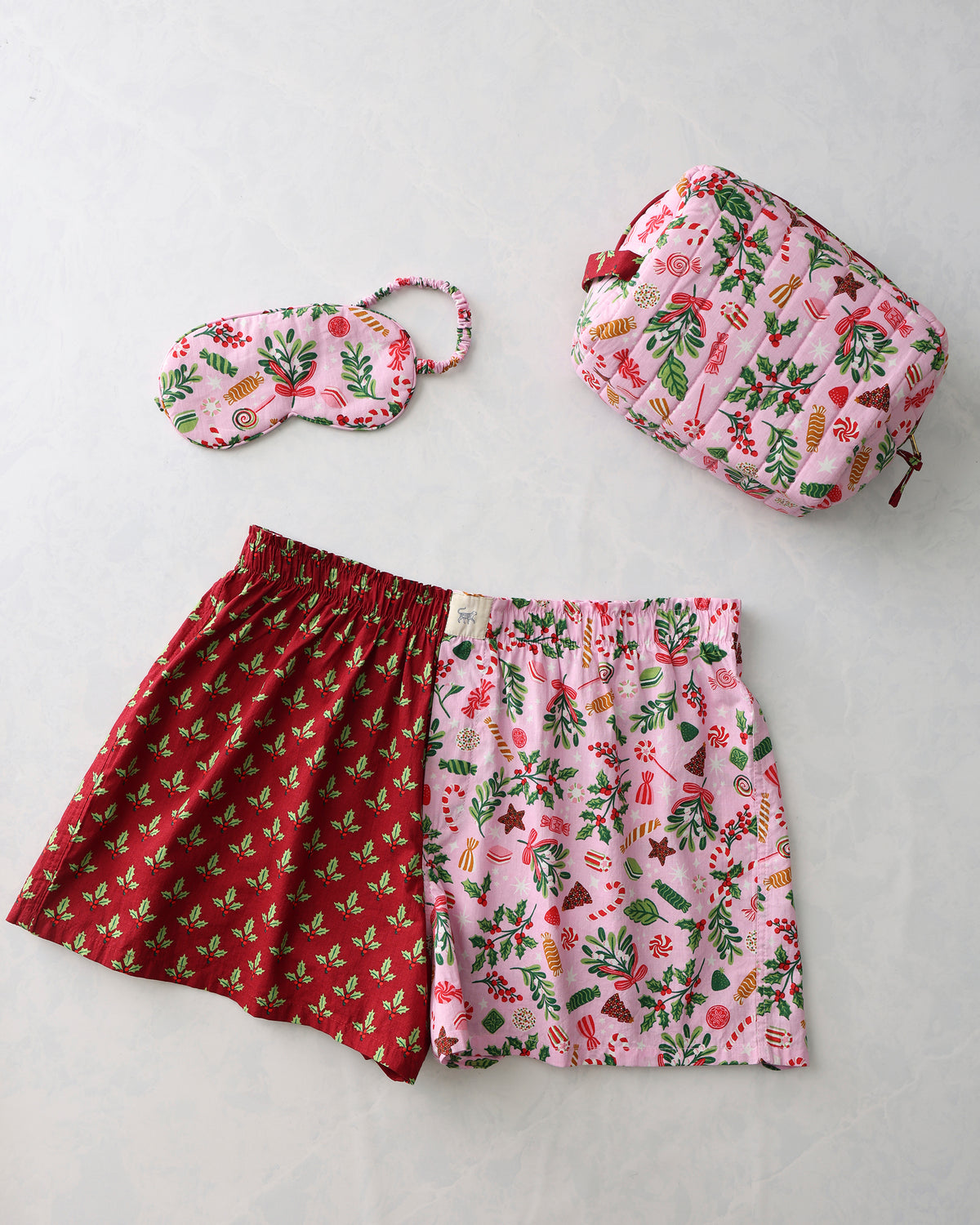 Holiday bundle with reversible boxer shorts, a pink patterned pouch, and a matching pink eye mask.