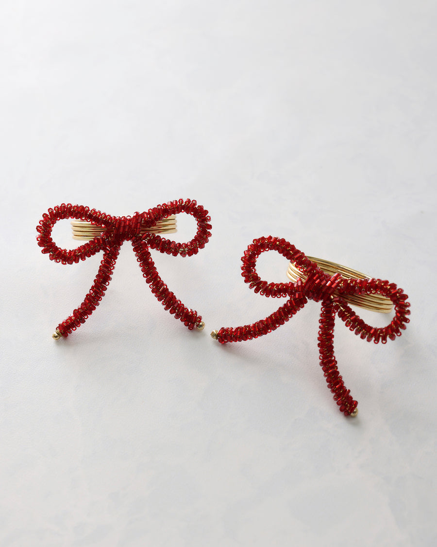 Two red beaded bow napkin rings displayed on a light background.