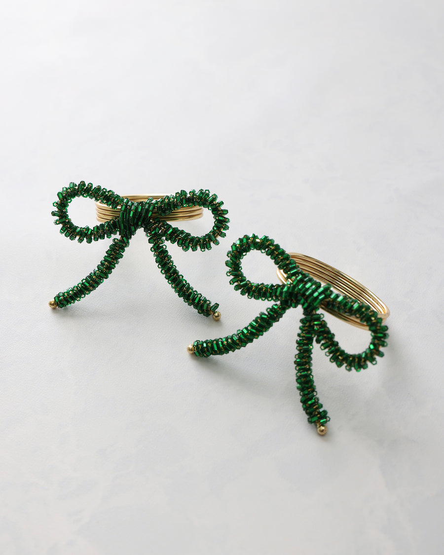 Two green beaded bow napkin rings displayed on a light background.