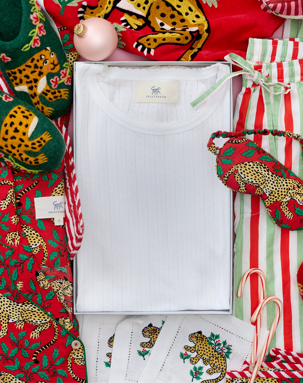 Flat lay of a white shirt in a box surrounded by leopard-print clothing and holiday accessories.