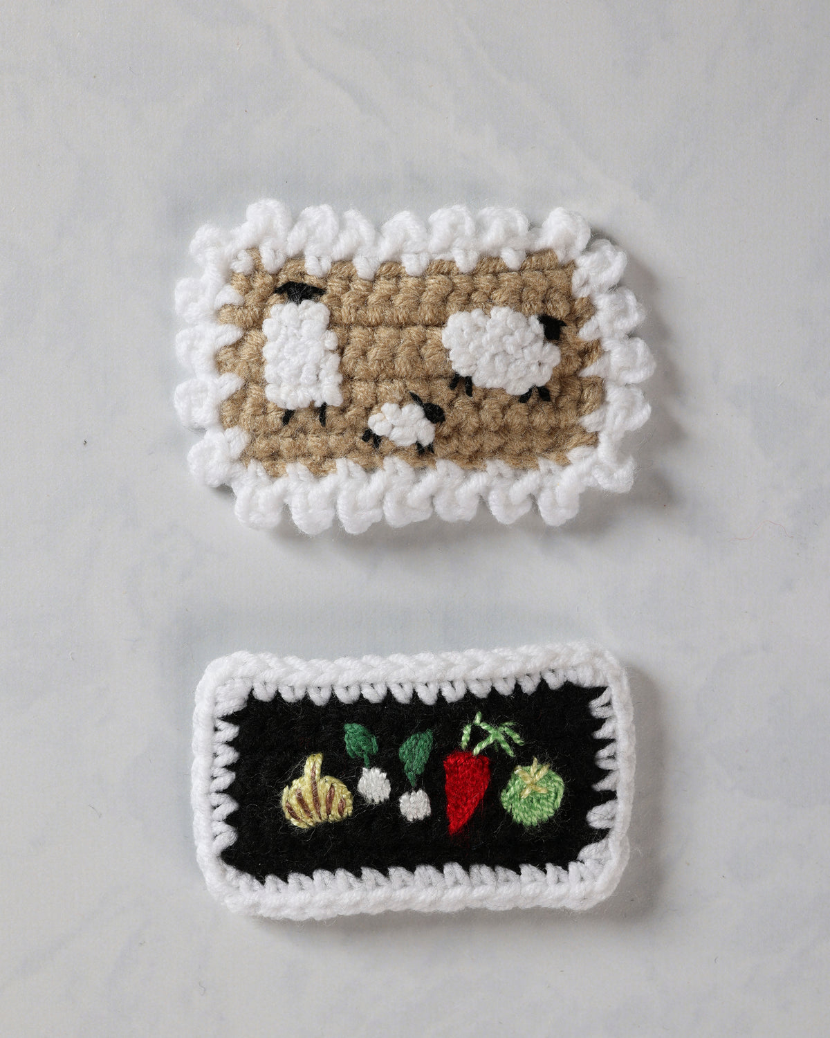 Two crochet snap hair clips, one with a sheep design and one with embroidered farm vegetables.