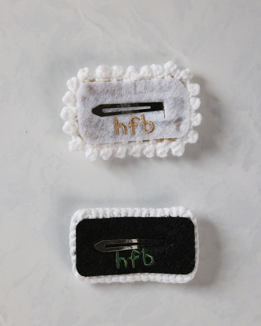 Backs of two crochet snap hair clips showing their metal clips and fabric backing.