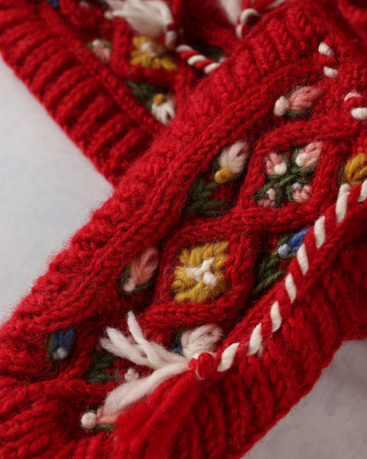 Close-up of the red slipper's hand-embroidered floral details and white-and-red tie.