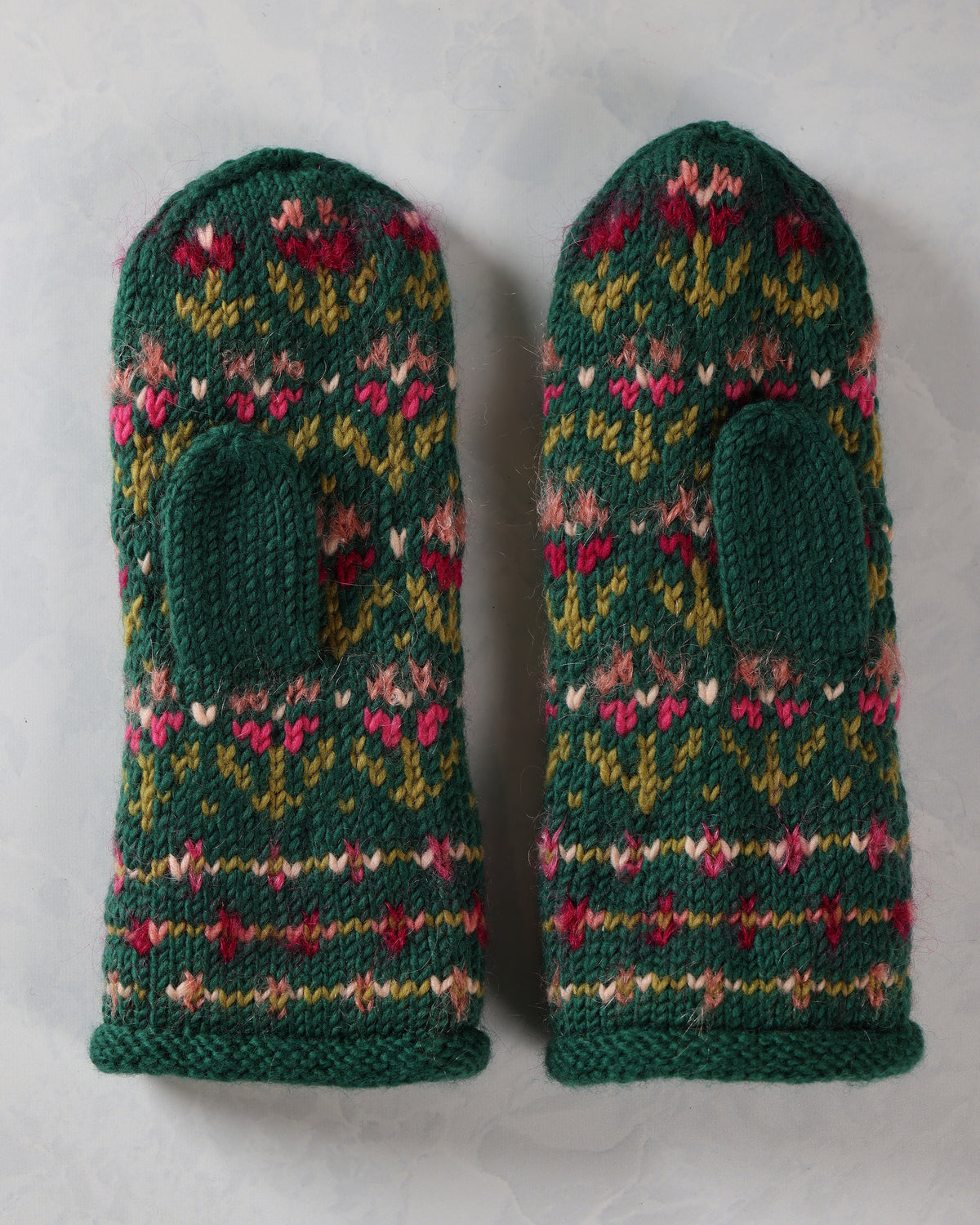 Pair of dark green knitted mittens with pink, red, yellow, and white floral patterns and thumb openings.