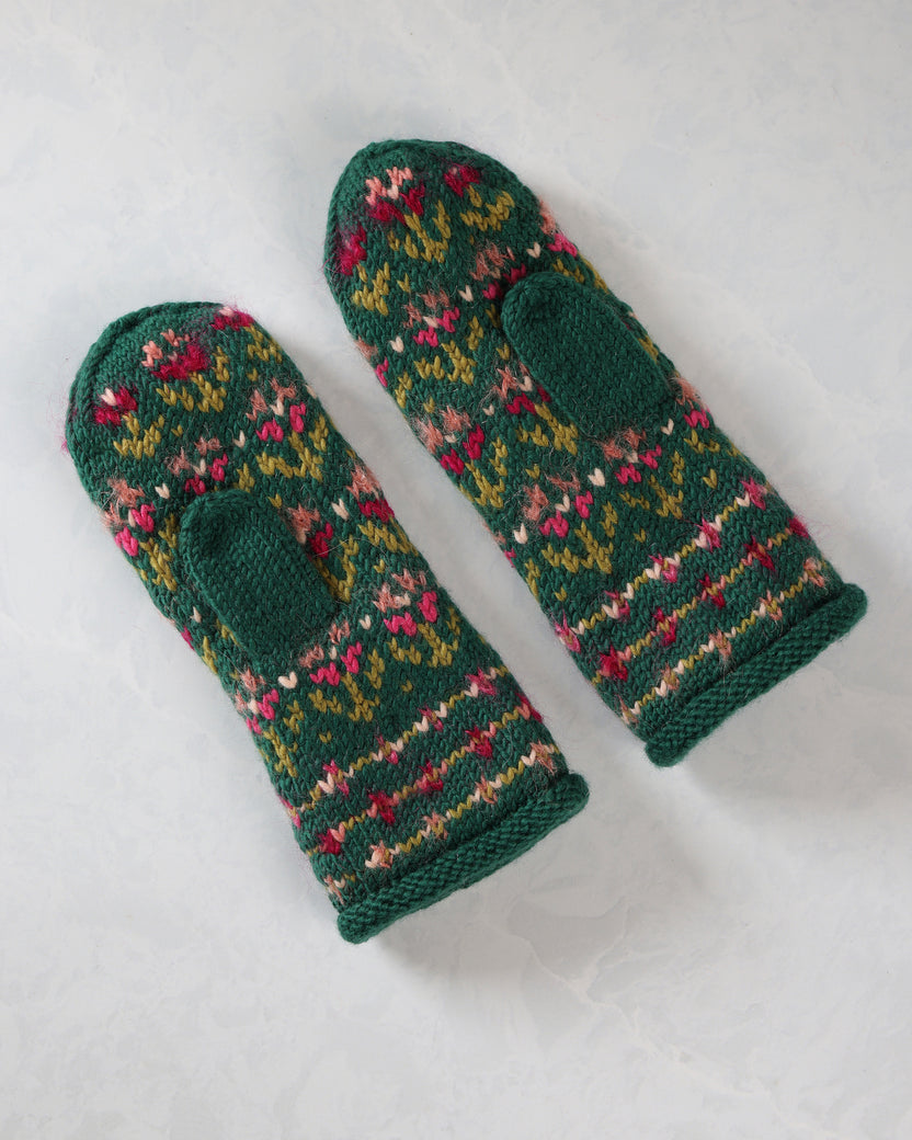Pair of patterned green knitted mittens shown at an angle with thumb openings and ribbed cuffs.