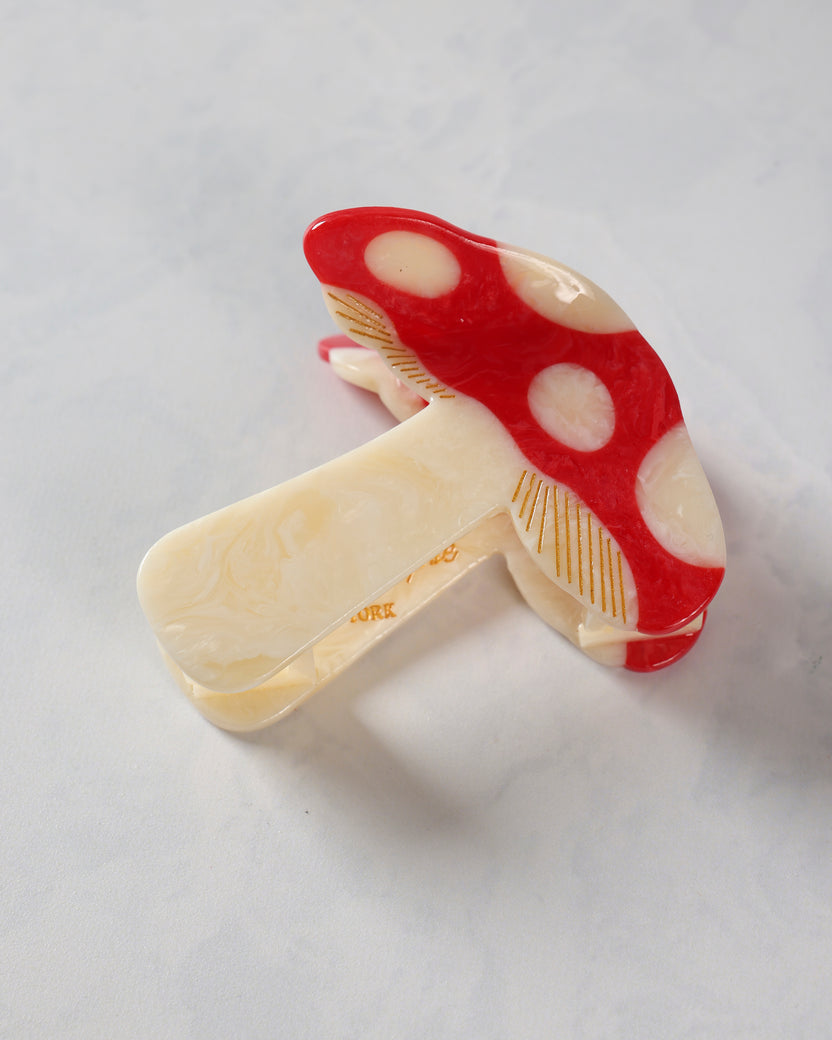 Red-and-cream mushroom-pattern claw hair clip shown closed from an angled view.