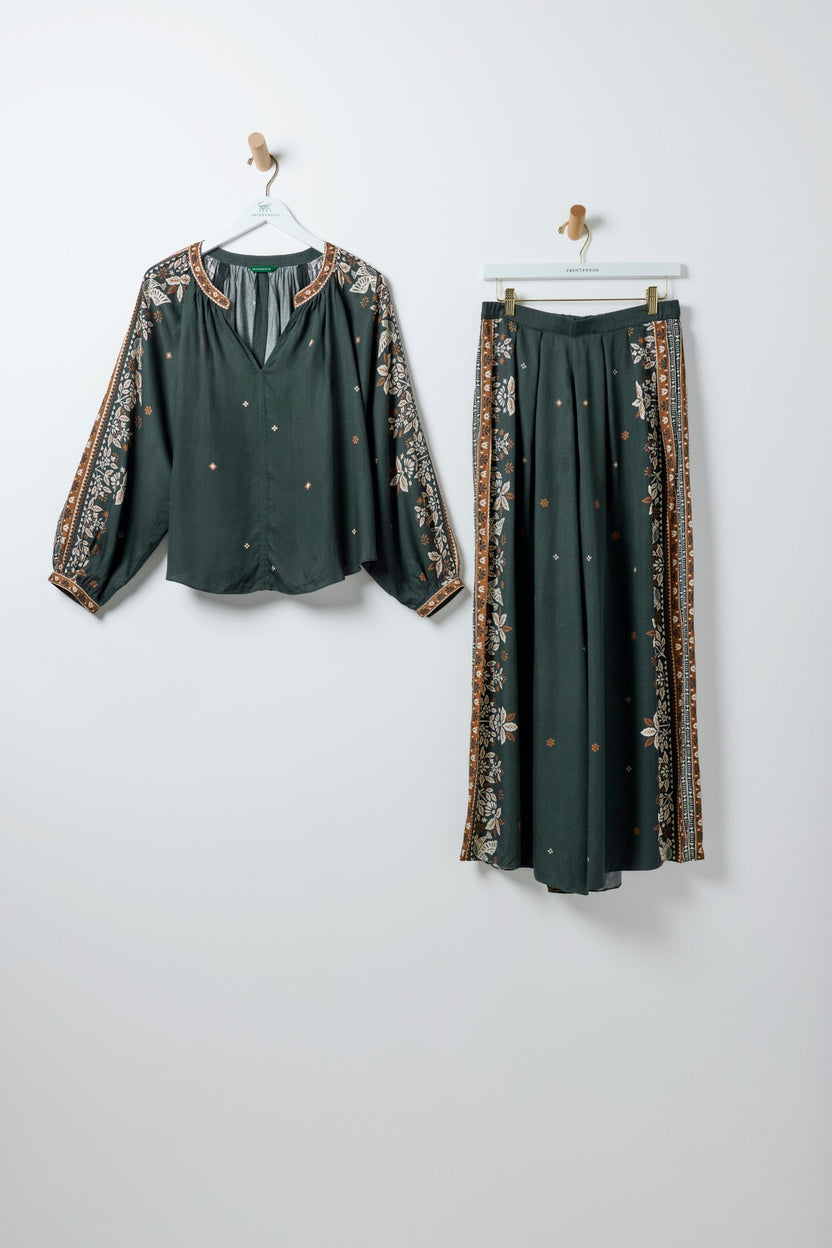 Spruce Hallie blouse and Sasha pants bundle hanging separately, with floral border patterns and small scattered motifs.