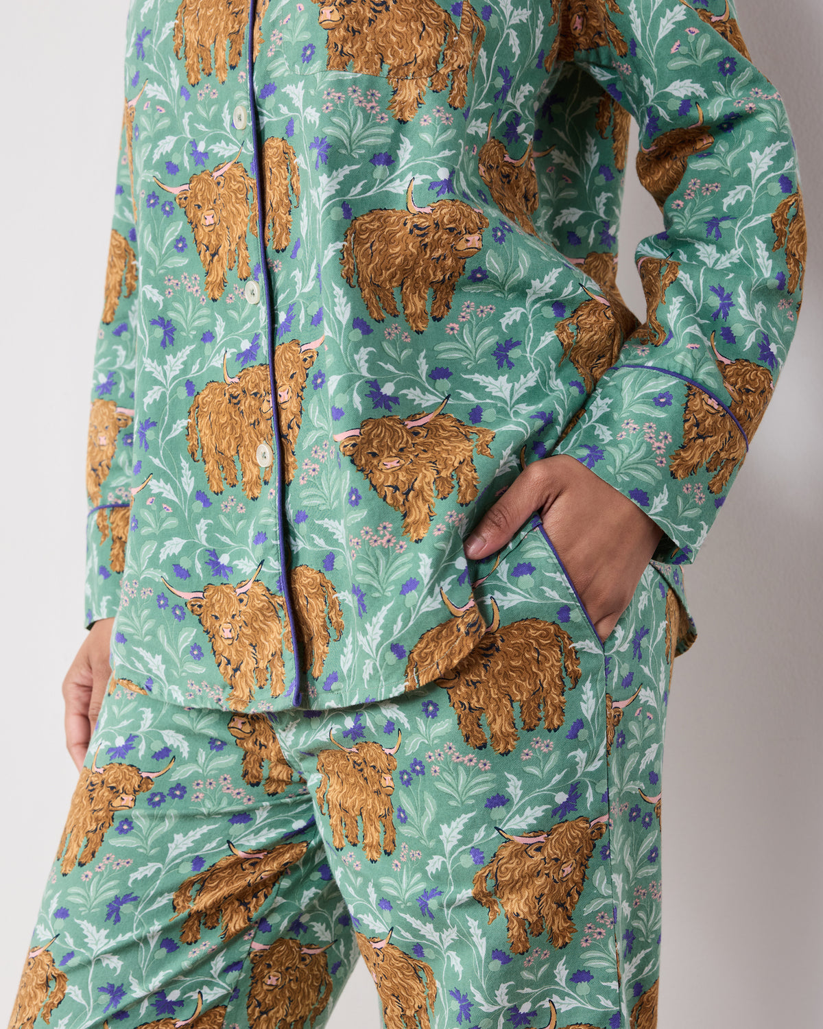 Close view of the Soft Thistle Highland Cows long pajama set showing the button-down top, chest pocket, pants pocket, and print.