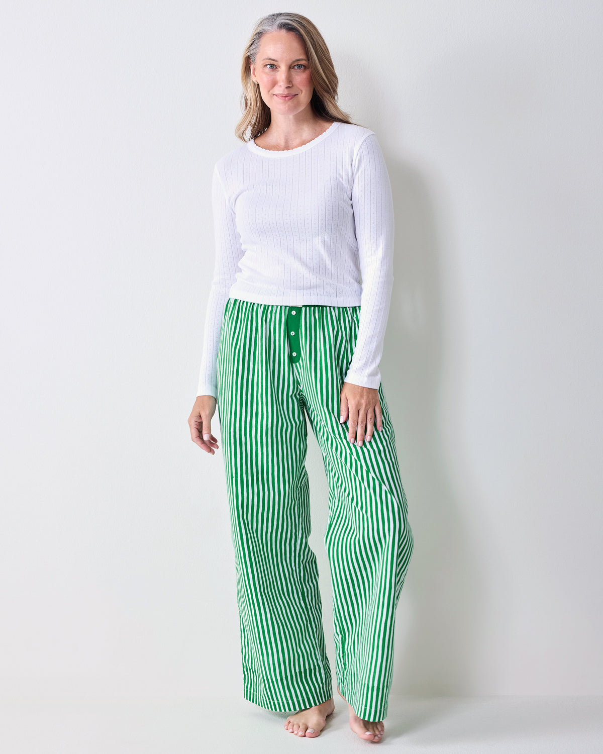 Front view of green-and-white vertically striped wide-leg pajama pants with a button-front waistband.