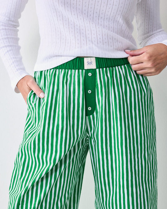 Close-up of the striped pajama pants showing the elastic waistband, button placket, side pocket, and inner label.