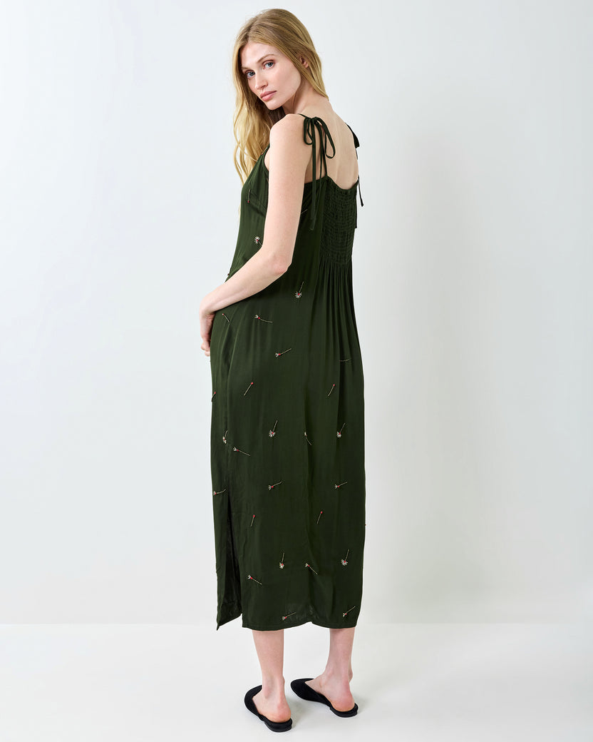 Back view of the olive Matchmaker Melody slip dress showing the smocked back, tie straps, and scattered decorative motifs.