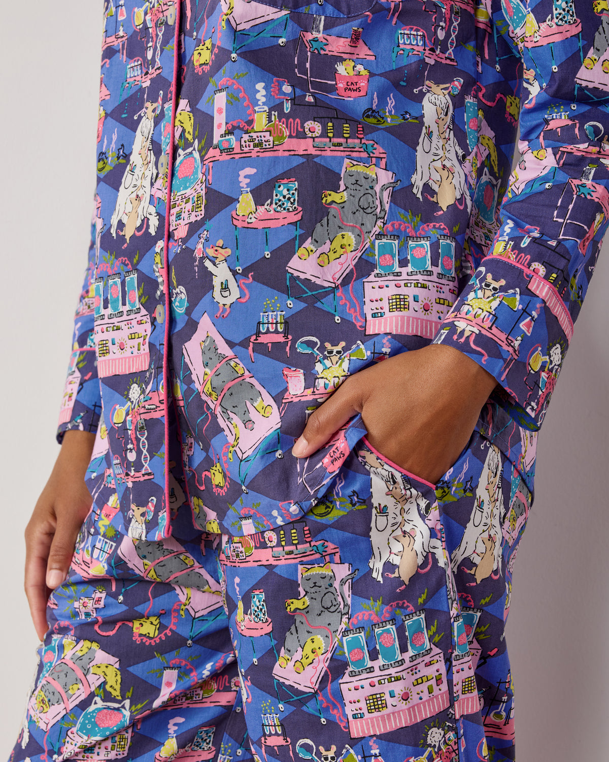 Person wearing a long-sleeved button-down pajama top and pants with a blue cat-and-mouse laboratory print.