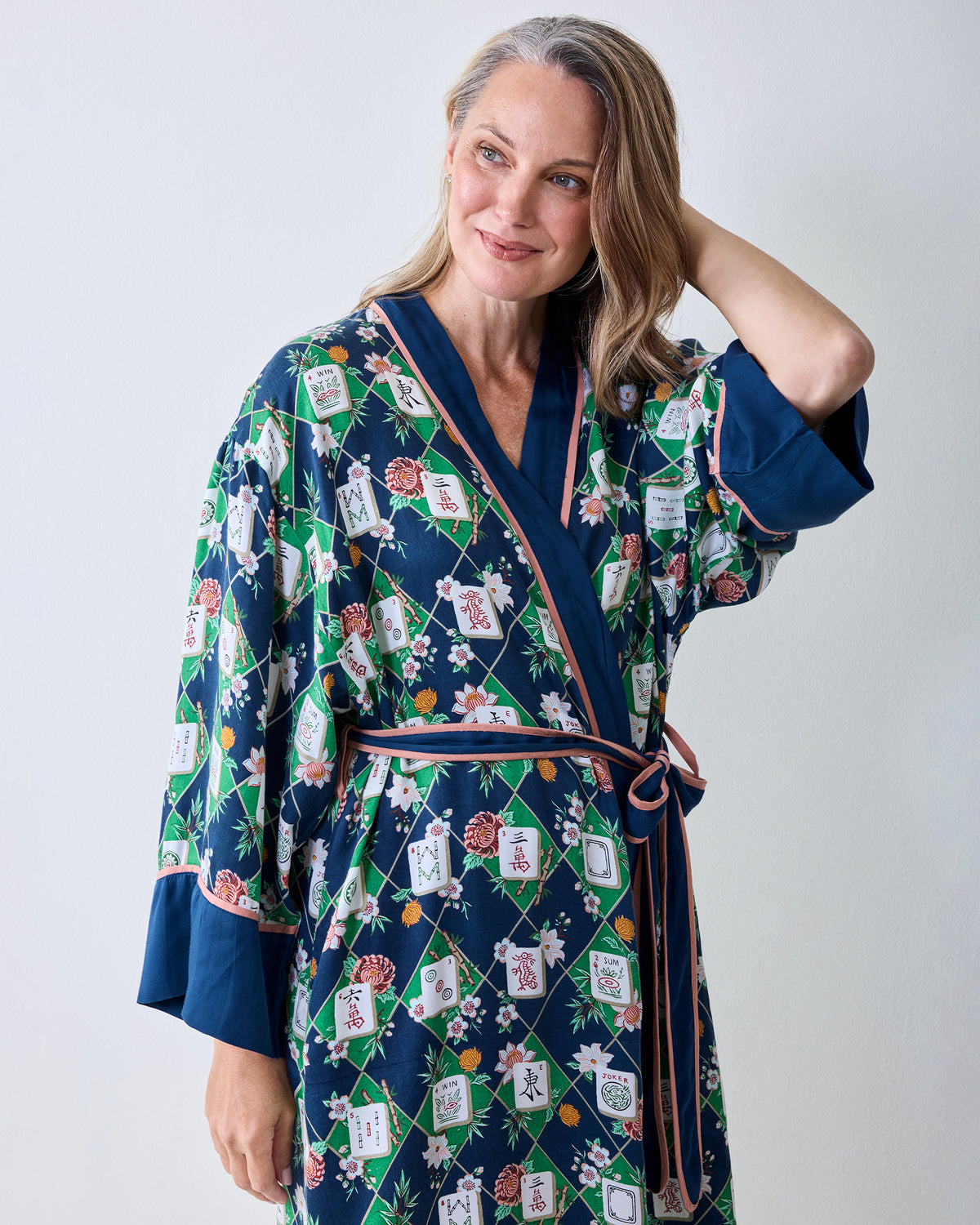 Close view of the wintergreen Mahj Garden robe showing its navy trim, pink waist ties, floral print, and patterned labels.