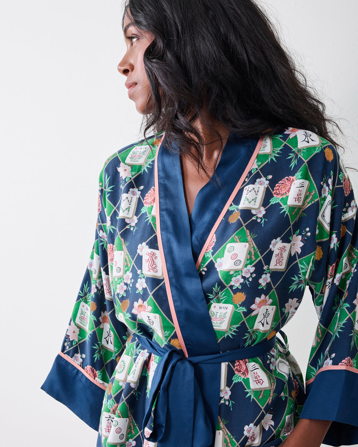 Mahj Garden wrap pajama set in a dark blue, green, and floral tile print, shown from the side with the belt tied at the waist.