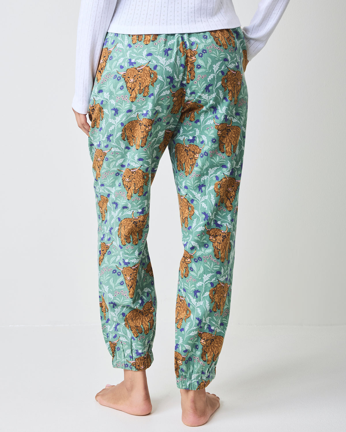 Back view of green Highland cow-print flannel joggers with elastic ankle cuffs