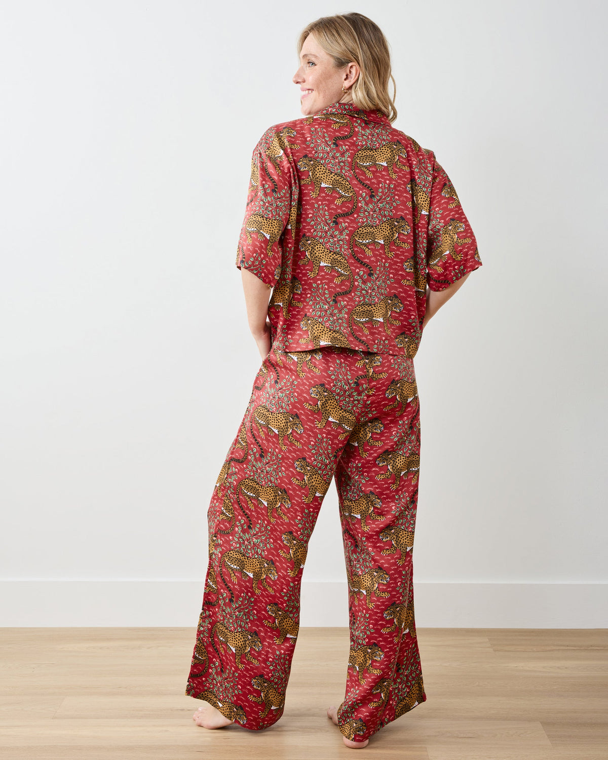Back view of a model wearing the scarlet Bagheera pajama set, showing the short-sleeve top and wide-leg pants with leopard-and-leaf print.