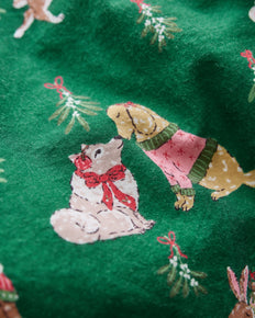 Close-up of a green printed surface with illustrated animals wearing clothing and small mistletoe motifs.