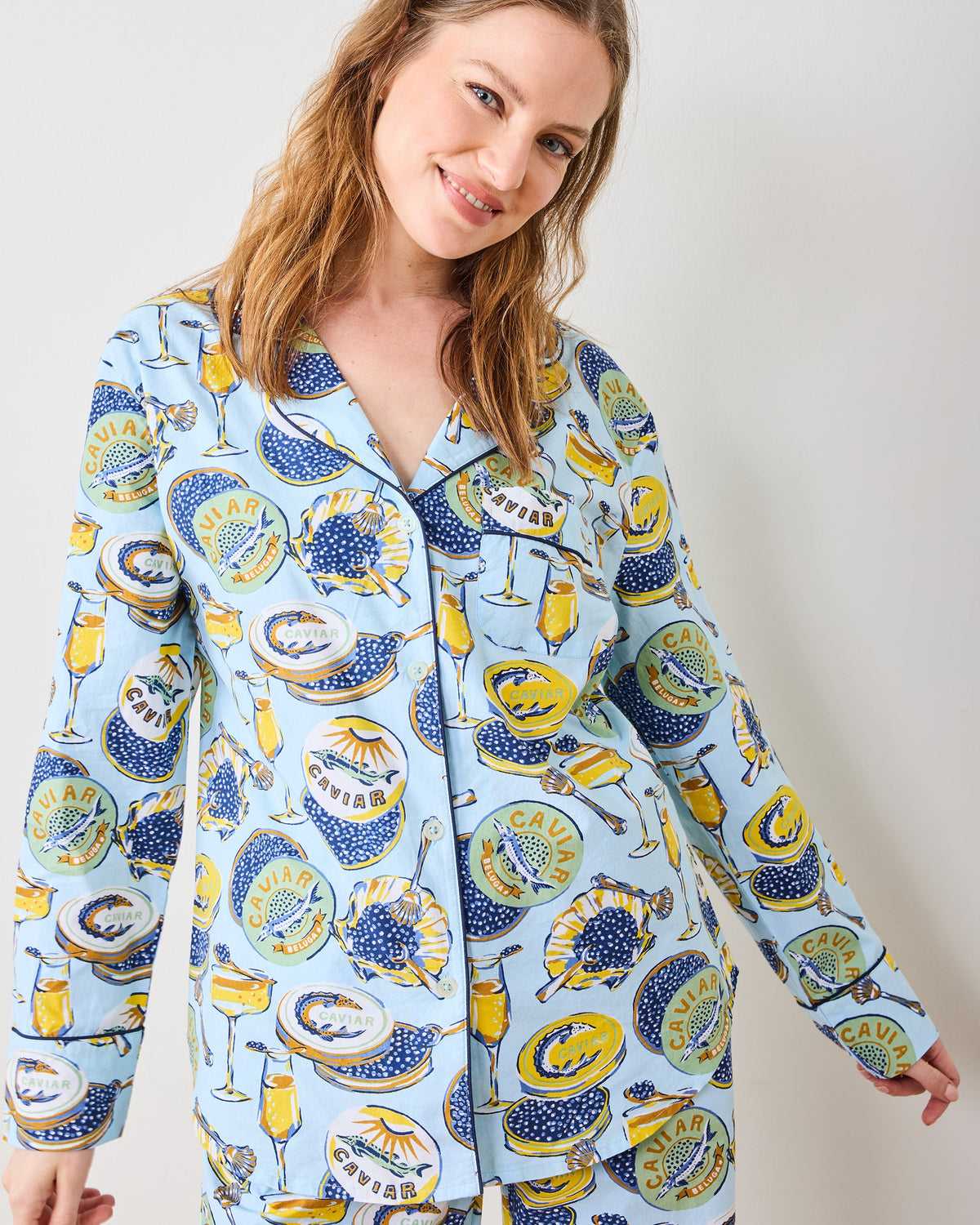 Close-up of the pale-blue Champagne and Caviar long pajama top with a notched collar, buttons, and caviar-and-champagne print.