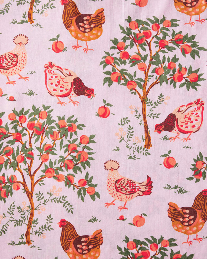 Close-up of the nightgown’s pink fabric print featuring hens, peaches, and fruit trees.