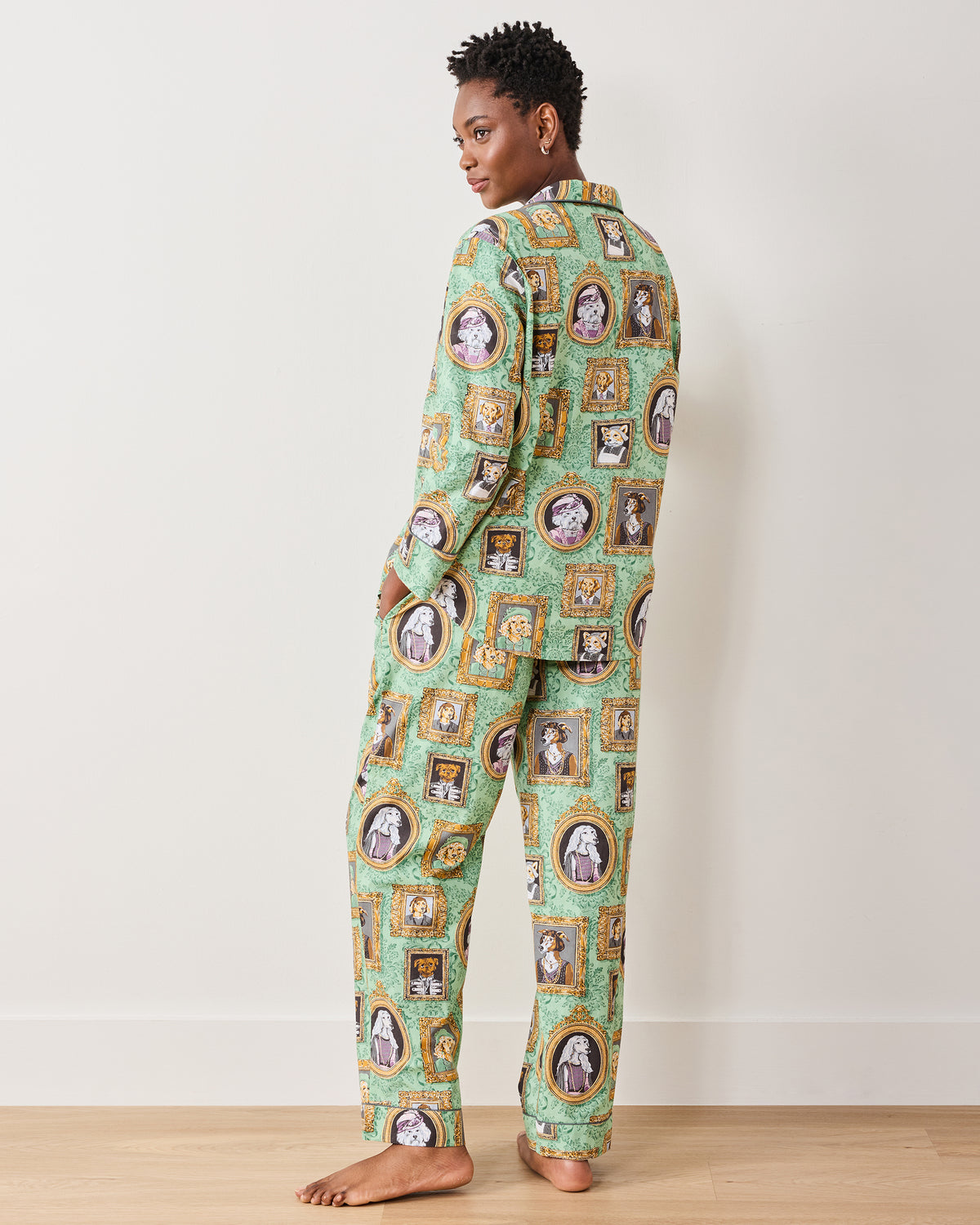 Three-quarter back view of a model wearing the green pajama set with framed dog portraits.