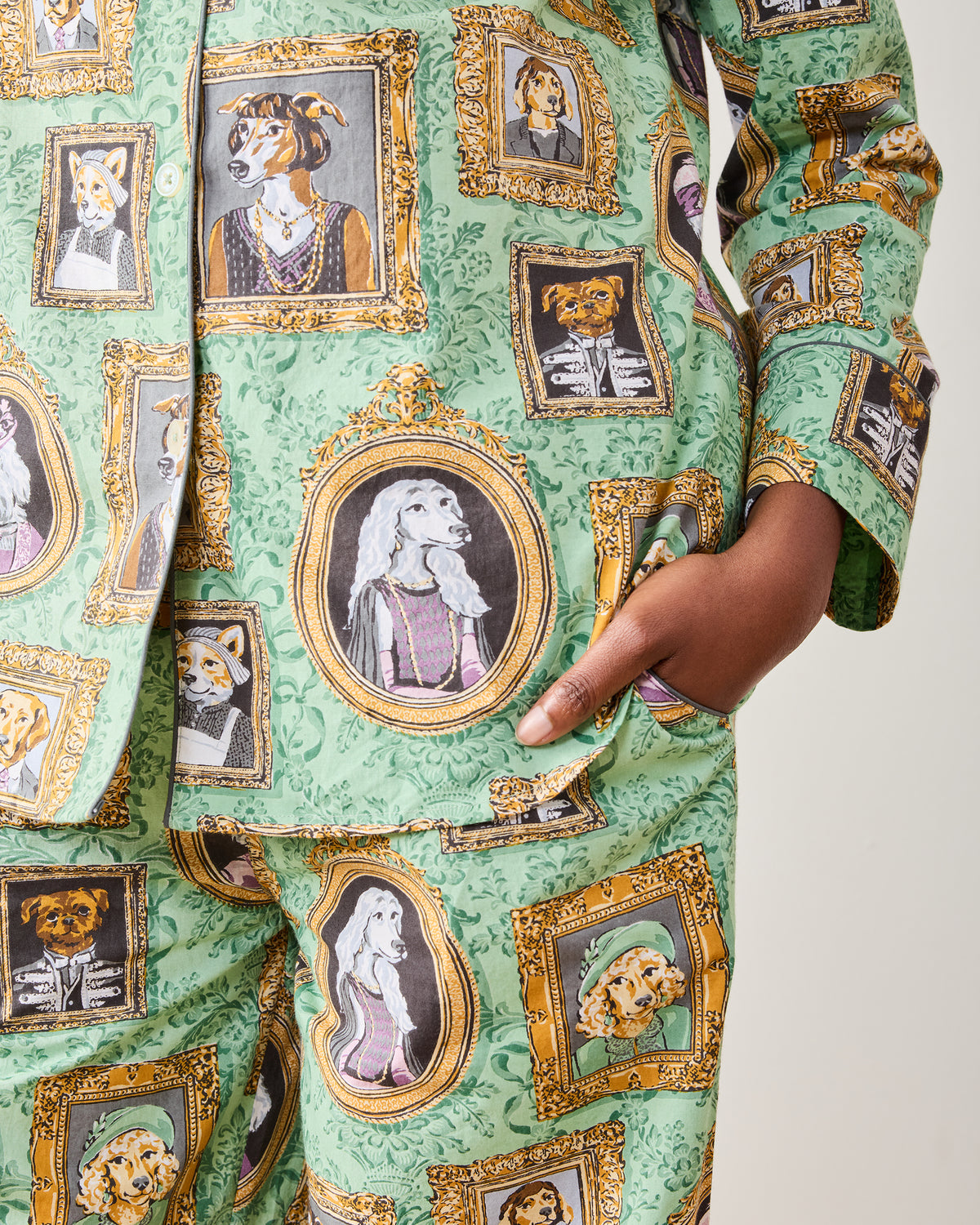 Close-up of the green pajama set showing framed dog portraits and a pants pocket.