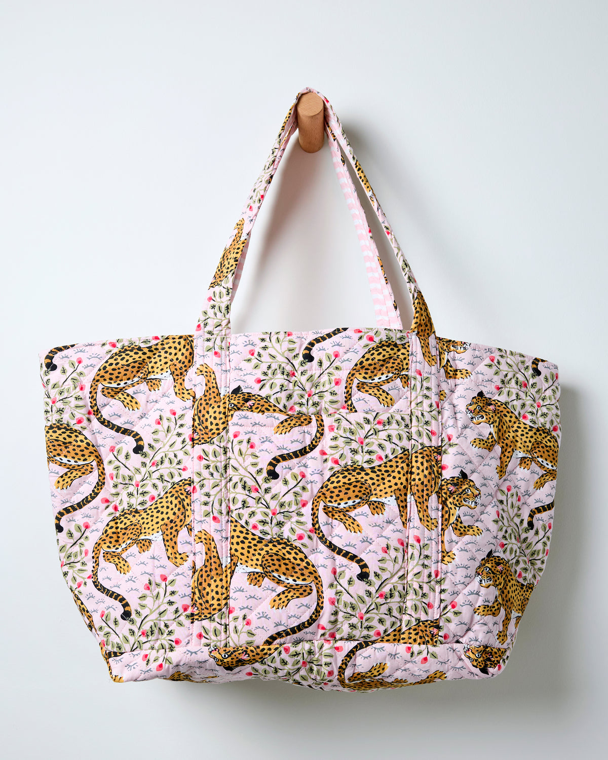 Front view of the blush Bagheera quilted weekend bag with spotted big-cat, leaf, and flower print.