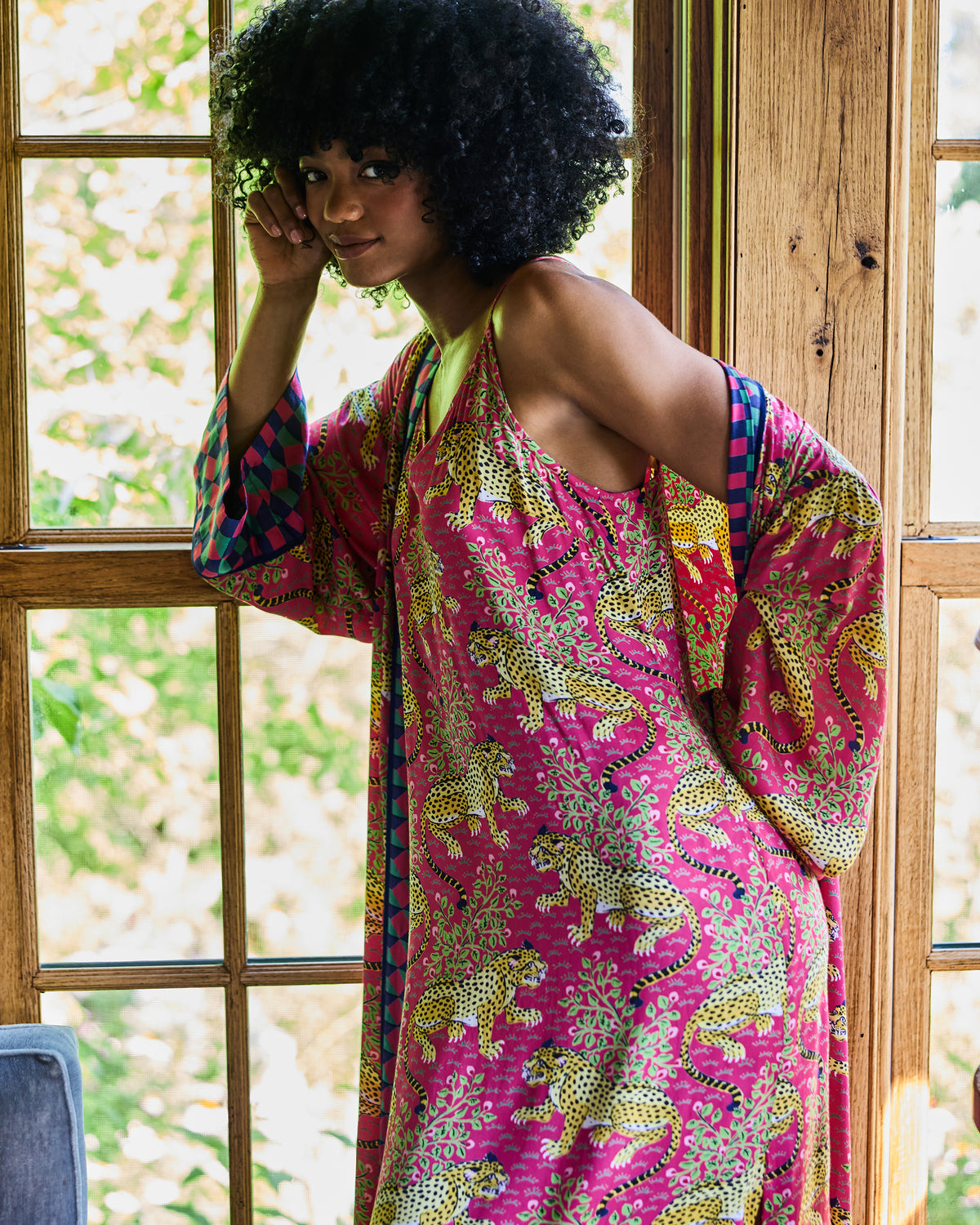 Side view of a person wearing the hot pink leopard-print nightie with the matching robe draped over the shoulders