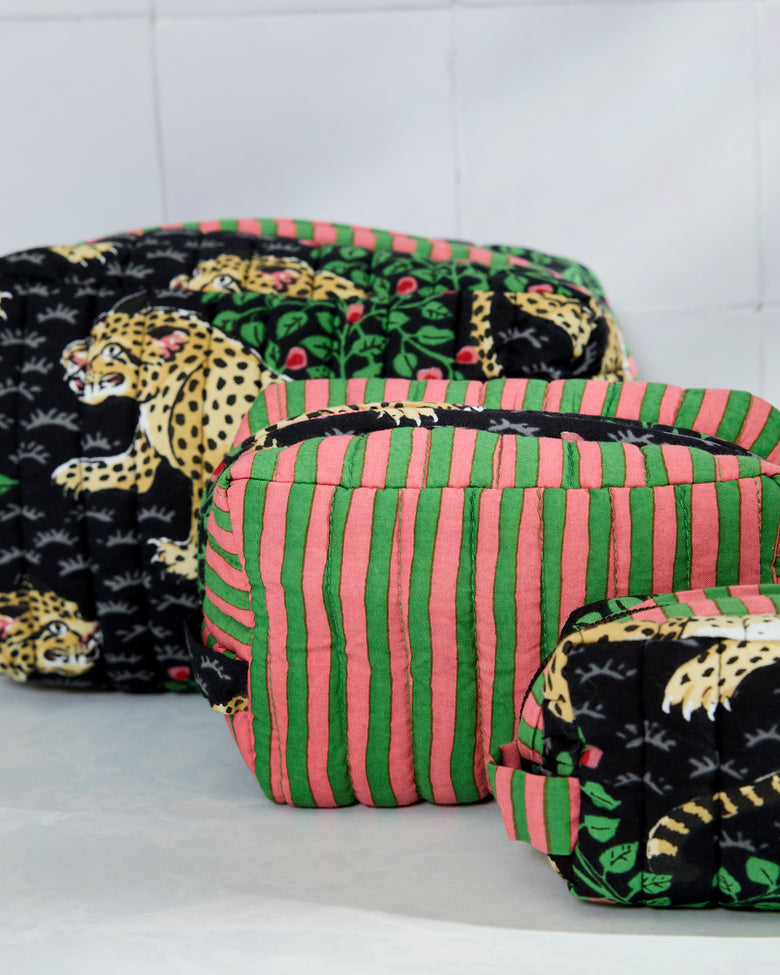 Close-up of three quilted pouches showing leopard print and pink-and-green striped fabric, with one pouch partially open.