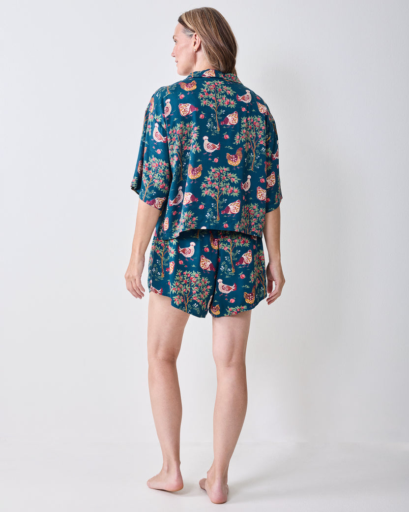 Back view of the navy Hen House short pajama set, showing the short-sleeved top and matching shorts with chicken-and-fruit print.