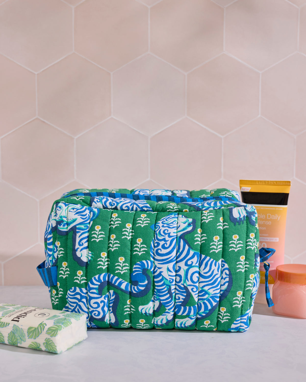 Green and blue quilted pouch with repeated blue-and-white tiger motifs and small white flowers.