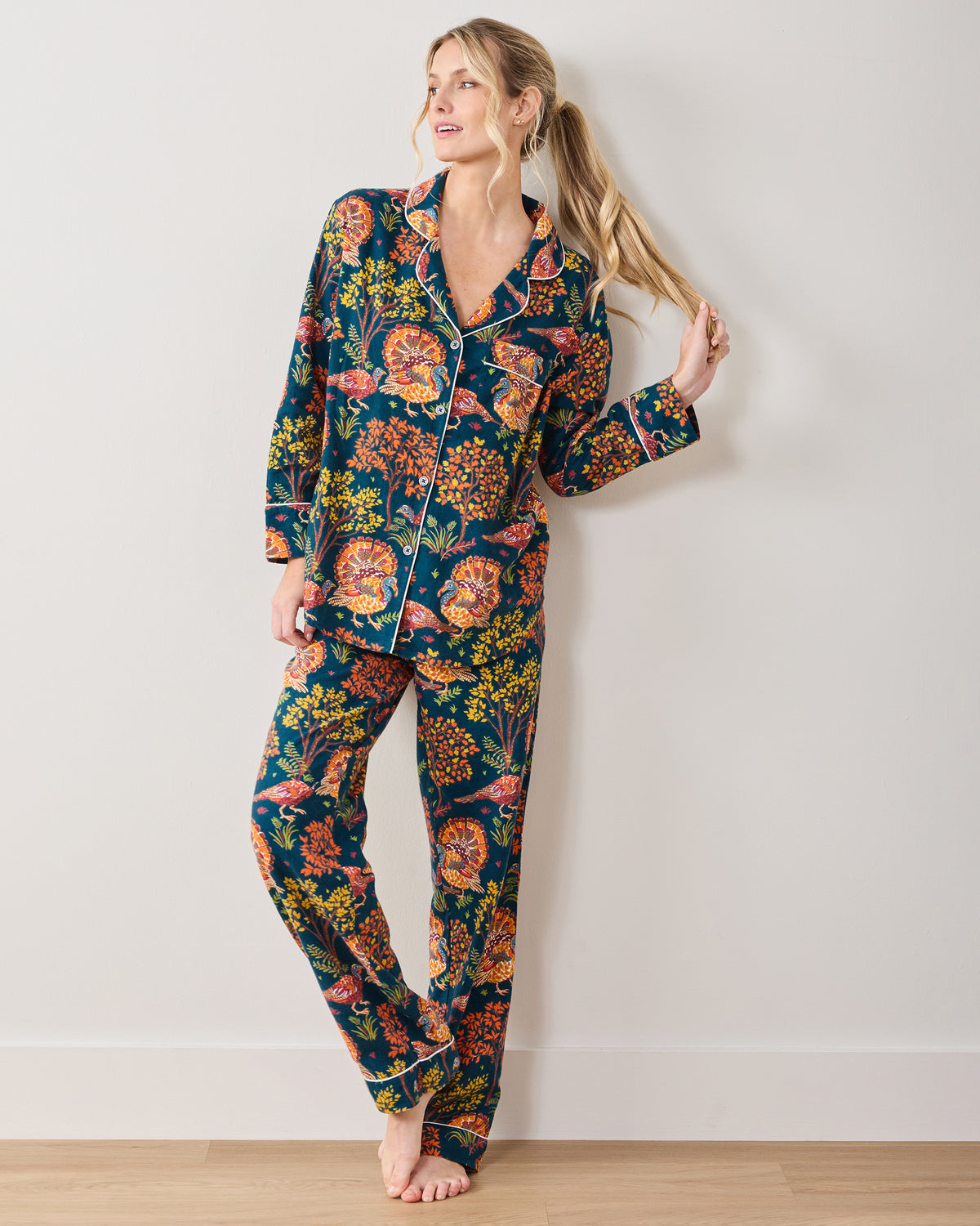 Front view of a model wearing the Turkey Trot navy long-sleeve pajama set with white piping and an autumn turkey print.