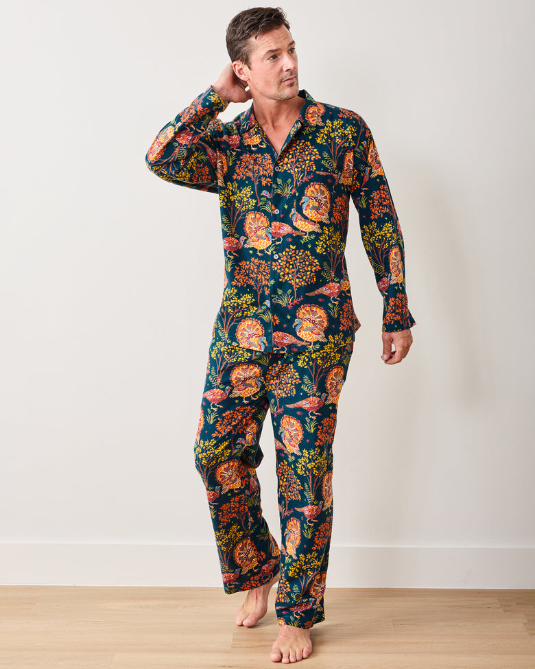 Full-length view of a model wearing the navy Turkey Trot long pajama set with colorful turkey and autumn foliage print.